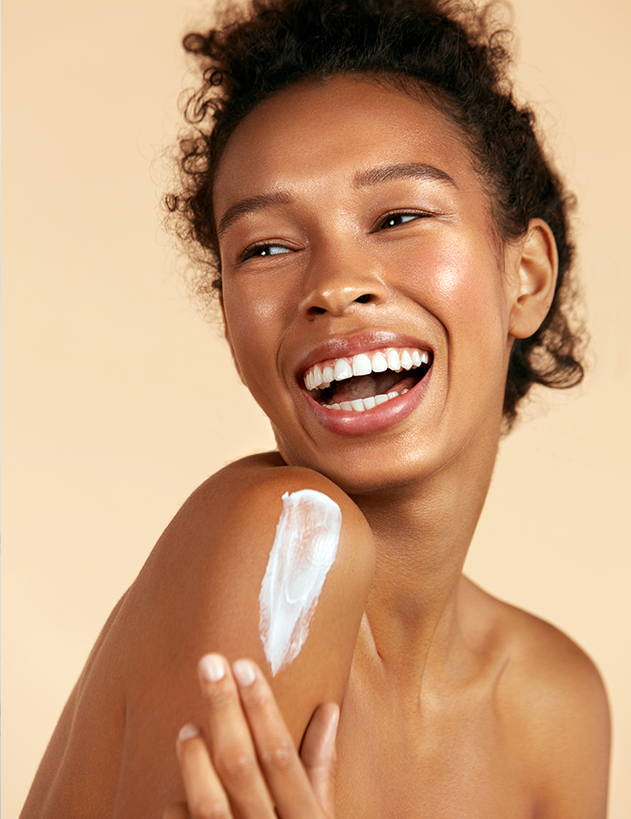Woman smiling with body cream on her shoulder